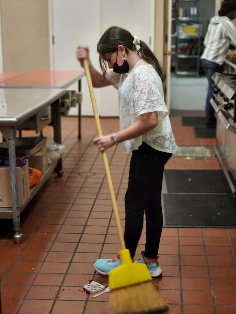 girl sweeping garbage off the floor